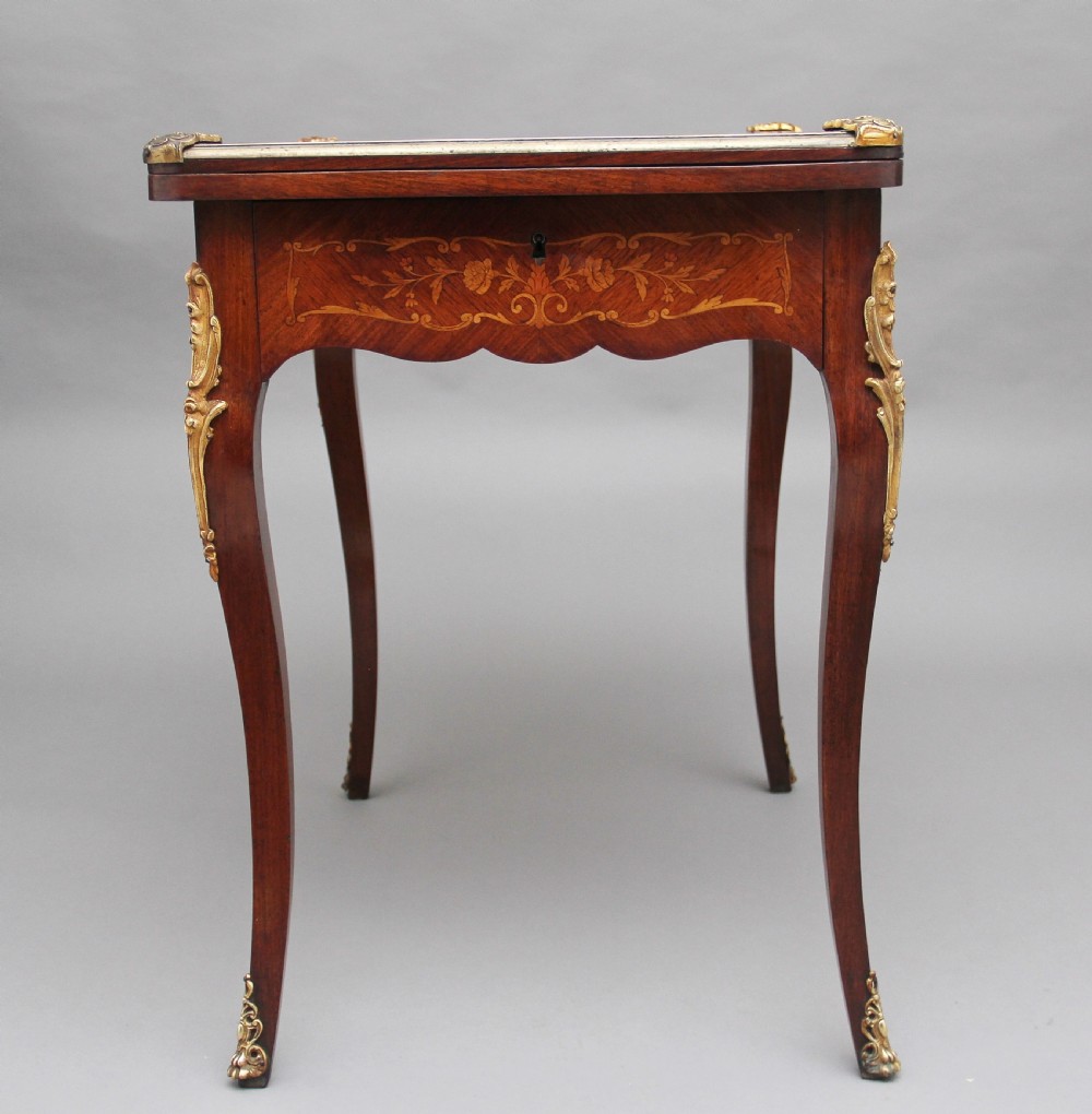 A 19th-century French Rococo revival kingwood fold-over card table with floral marquetry inlay, cabriole legs, and ornate gilt ormolu mounts. View XII