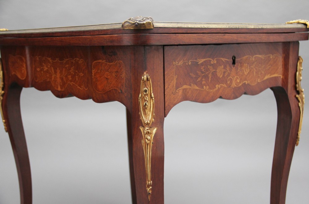 A 19th-century French Rococo revival kingwood fold-over card table with floral marquetry inlay, cabriole legs, and ornate gilt ormolu mounts. View XIV
