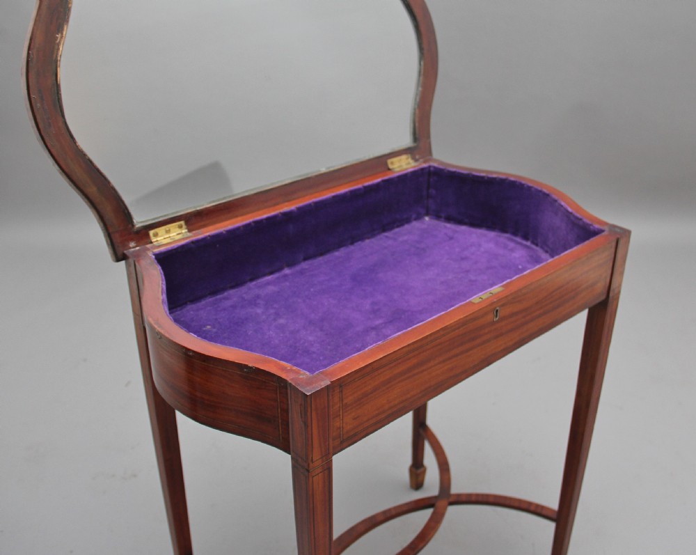An Edwardian inlaid satinwood bijouterie table featuring a glazed rectangular top, curved side profile, tapered square legs, and curved cross-stretchers. View III