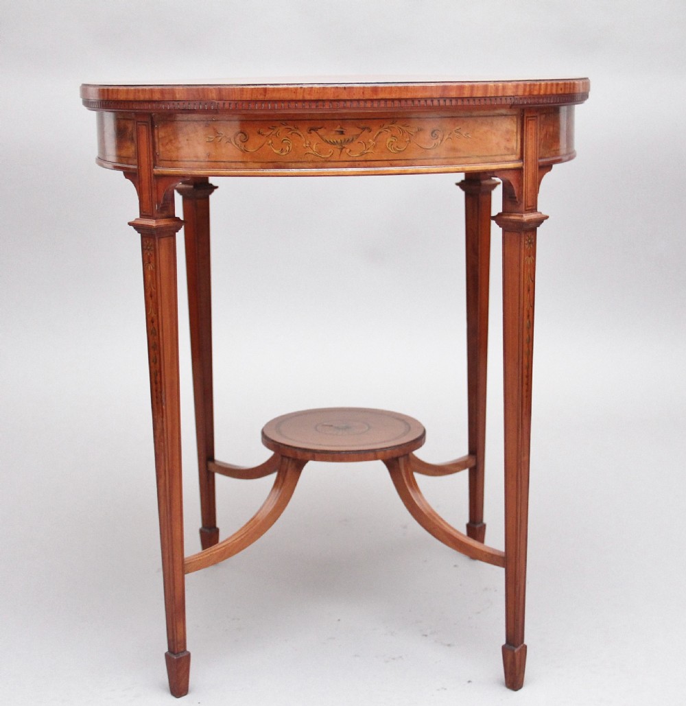 An oval 19th-century satinwood occasional table featuring floral marquetry along the apron, tapered square legs, and a small circular undertier. View V