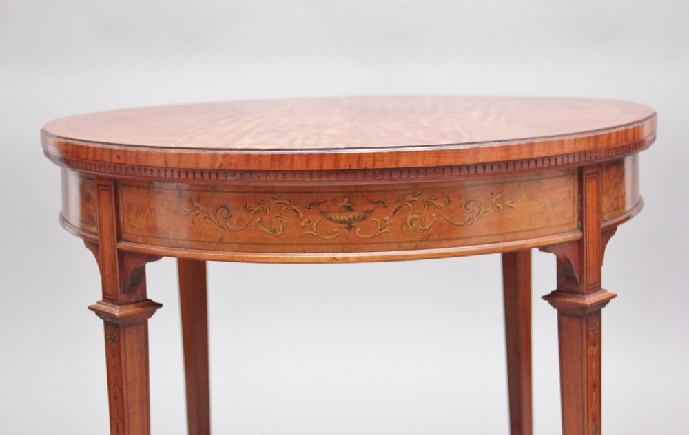 An oval 19th-century satinwood occasional table featuring floral marquetry along the apron, tapered square legs, and a small circular undertier. View VI