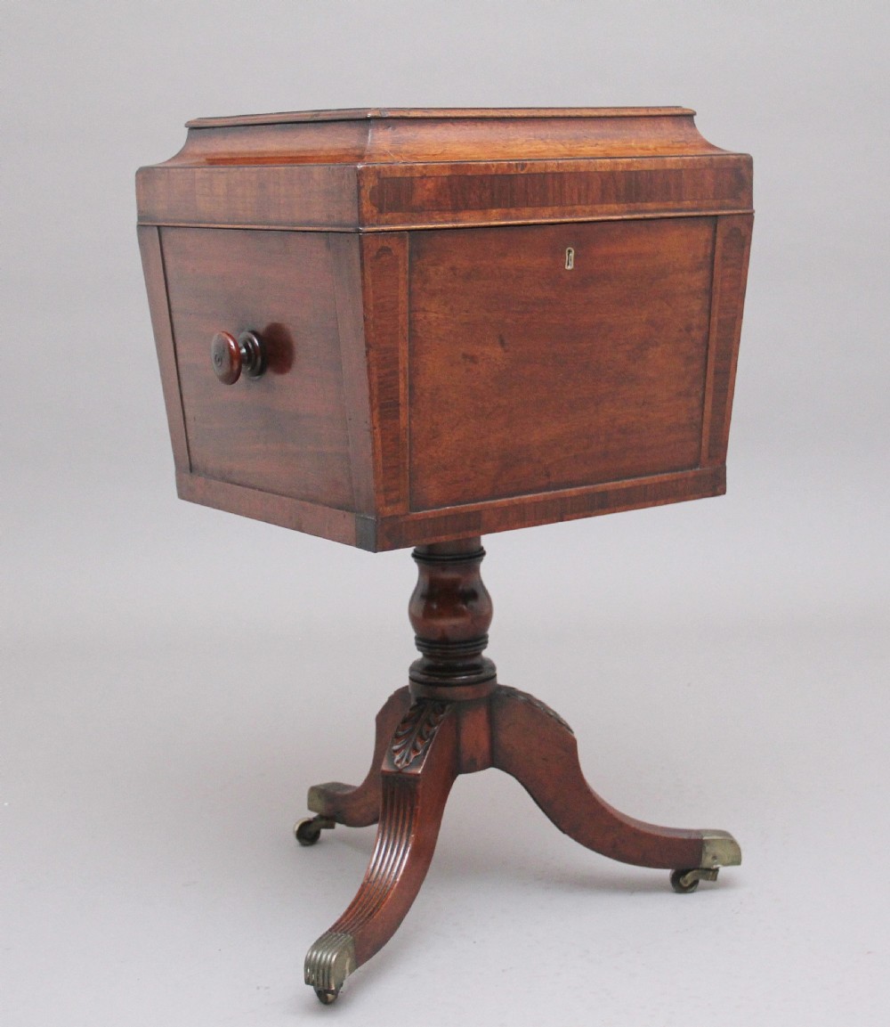 An early 19th-century Regency mahogany teapoy with a hinged tapered box mounted on a turned pedestal and reeded tripod legs with brass castors.