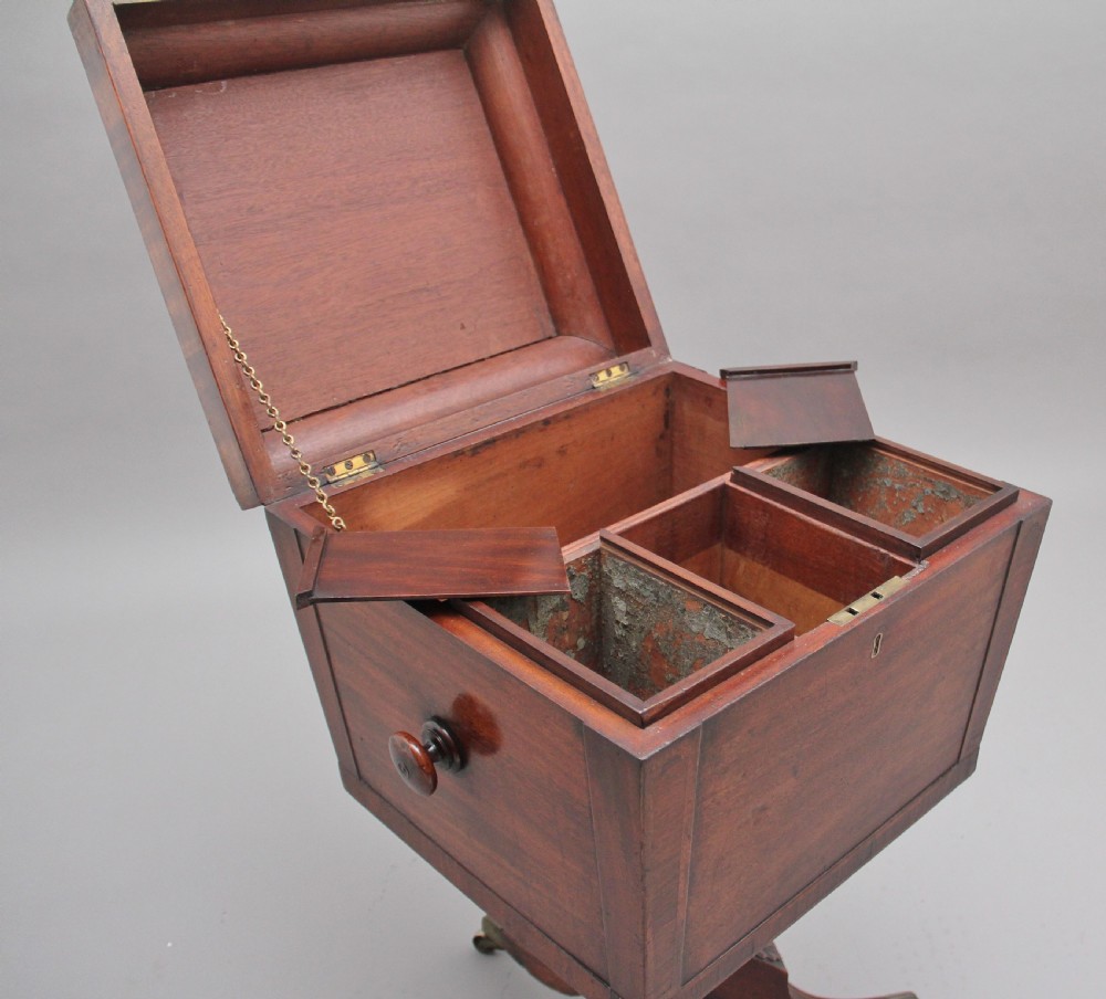 An early 19th-century Regency mahogany teapoy with a hinged tapered box mounted on a turned pedestal and reeded tripod legs with brass castors. View IV