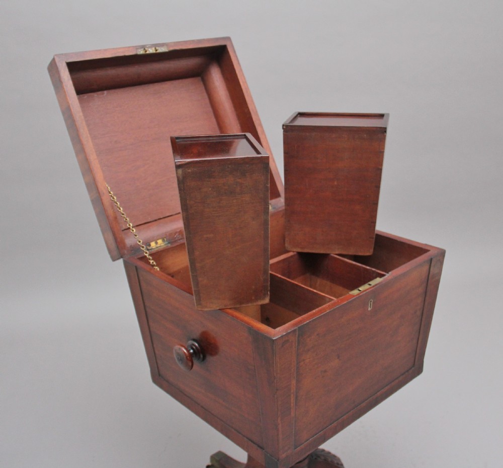 An early 19th-century Regency mahogany teapoy with a hinged tapered box mounted on a turned pedestal and reeded tripod legs with brass castors. View V