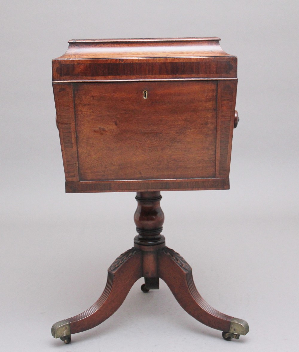 An early 19th-century Regency mahogany teapoy with a hinged tapered box mounted on a turned pedestal and reeded tripod legs with brass castors. View VI