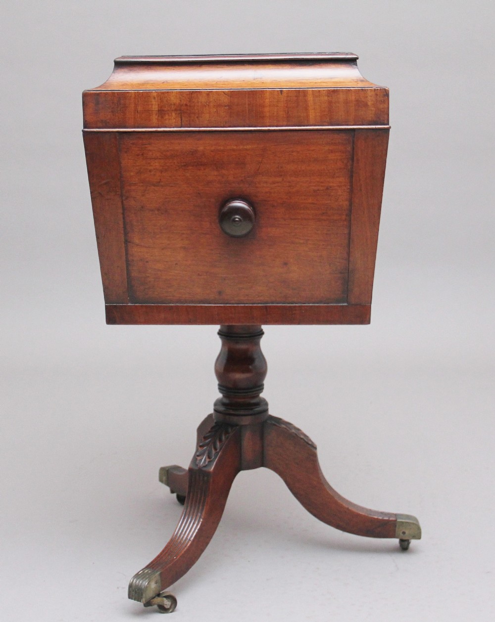 An early 19th-century Regency mahogany teapoy with a hinged tapered box mounted on a turned pedestal and reeded tripod legs with brass castors. View VII
