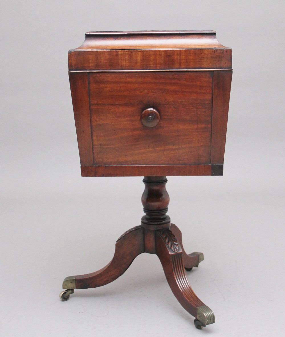 An early 19th-century Regency mahogany teapoy with a hinged tapered box mounted on a turned pedestal and reeded tripod legs with brass castors. View IX