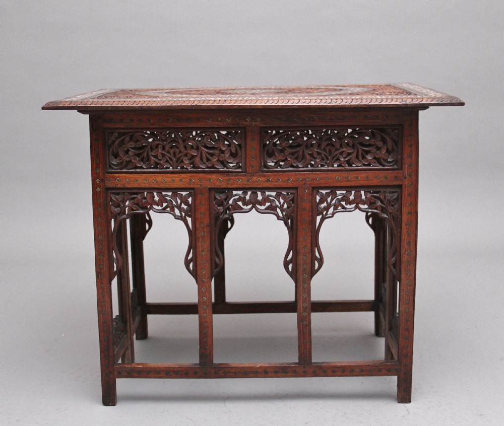 A 19th-century dark hardwood Indian occasional table featuring intricately carved floral fretwork panels, cusped arches, and a geometric bone-inlaid tabletop. View II