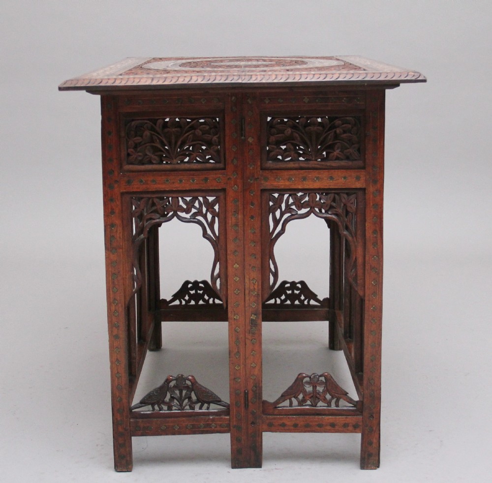 A 19th-century dark hardwood Indian occasional table featuring intricately carved floral fretwork panels, cusped arches, and a geometric bone-inlaid tabletop. View V