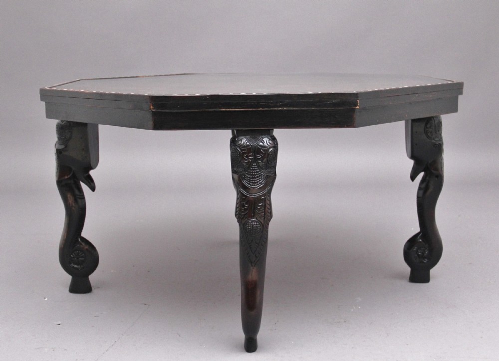 An octagonal wooden coffee table featuring detailed pictorial wood marquetry depicting an Indian village scene surrounded by a relief-carved floral border and ebonised outer rim. View III