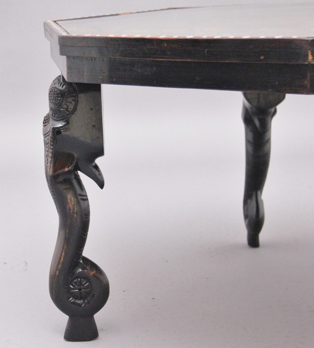 An octagonal wooden coffee table featuring detailed pictorial wood marquetry depicting an Indian village scene surrounded by a relief-carved floral border and ebonised outer rim. View X