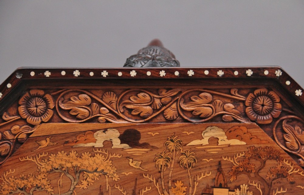 An octagonal wooden coffee table featuring detailed pictorial wood marquetry depicting an Indian village scene surrounded by a relief-carved floral border and ebonised outer rim. View XIV