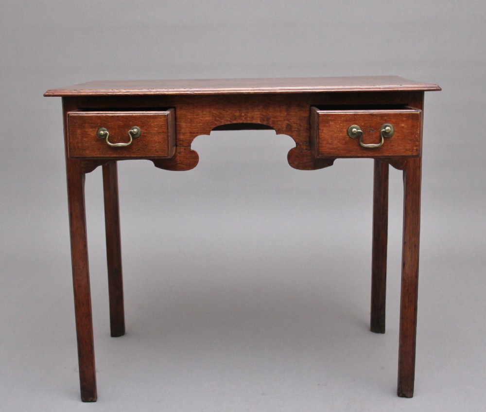 An early 19th-century oak lowboy side table featuring two drawers with brass handles, a shaped lower apron, and four straight legs. View II