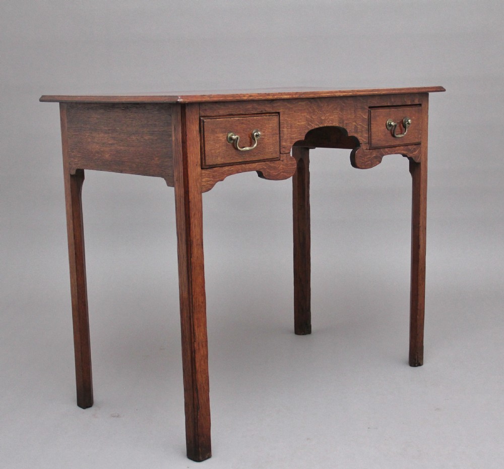 An early 19th-century oak lowboy side table featuring two drawers with brass handles, a shaped lower apron, and four straight legs. View III