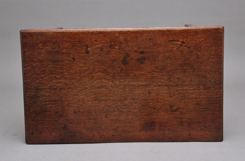 An early 19th-century oak lowboy side table featuring two drawers with brass handles, a shaped lower apron, and four straight legs. View X