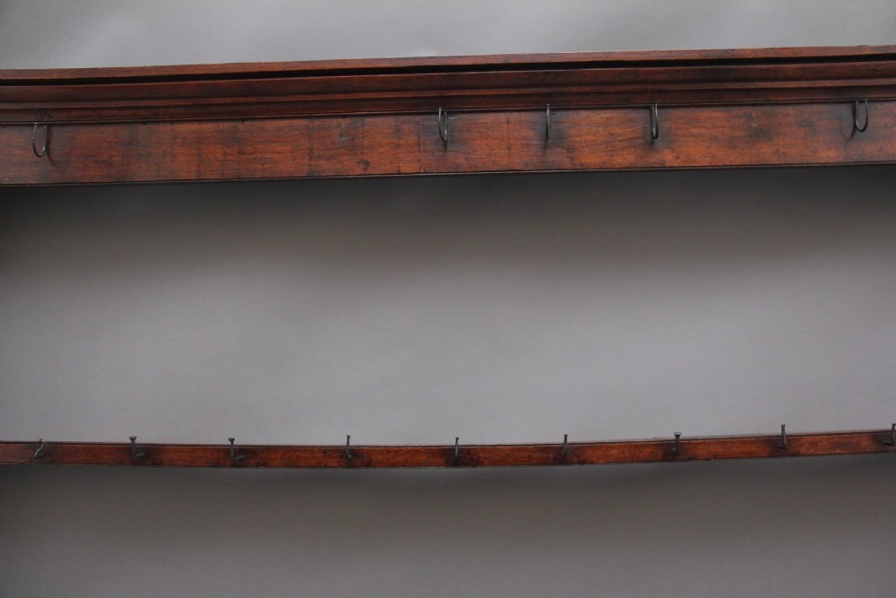 An 18th-century oak wall-mounted hanging rack featuring a moulded top cornice, open shelves, and embedded iron hooks. View III