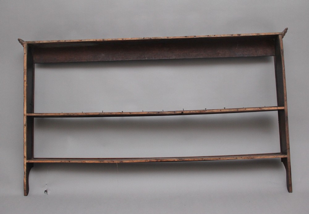 An 18th-century oak wall-mounted hanging rack featuring a moulded top cornice, open shelves, and embedded iron hooks. View VI