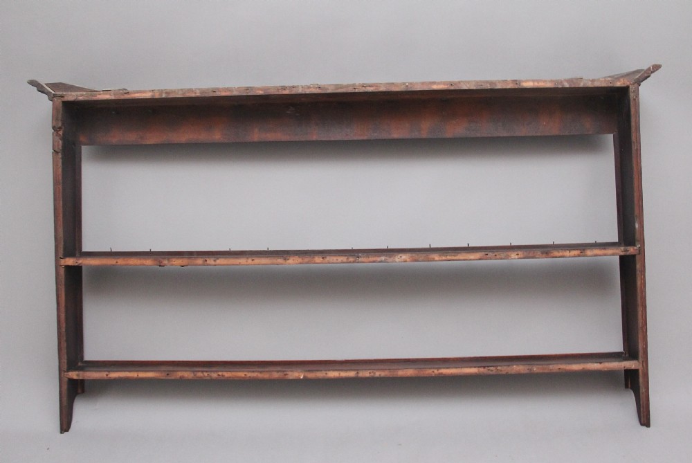 An 18th-century dark oak wall-mounted hanging rack featuring a moulded top cornice and two horizontal rails set with metal hooks. View V