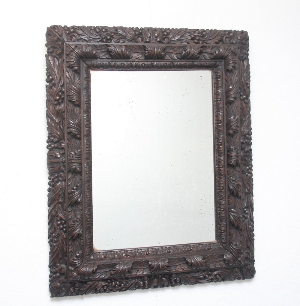 A rectangular 18th century wall mirror featuring a deeply carved dark oak frame with acanthus leaf motifs.