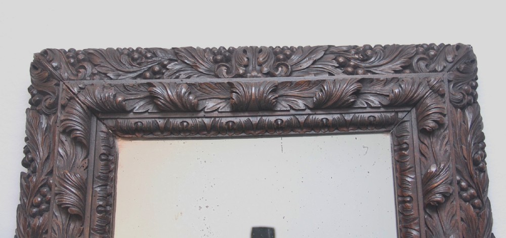 A rectangular 18th century wall mirror featuring a deeply carved dark oak frame with acanthus leaf motifs. View II