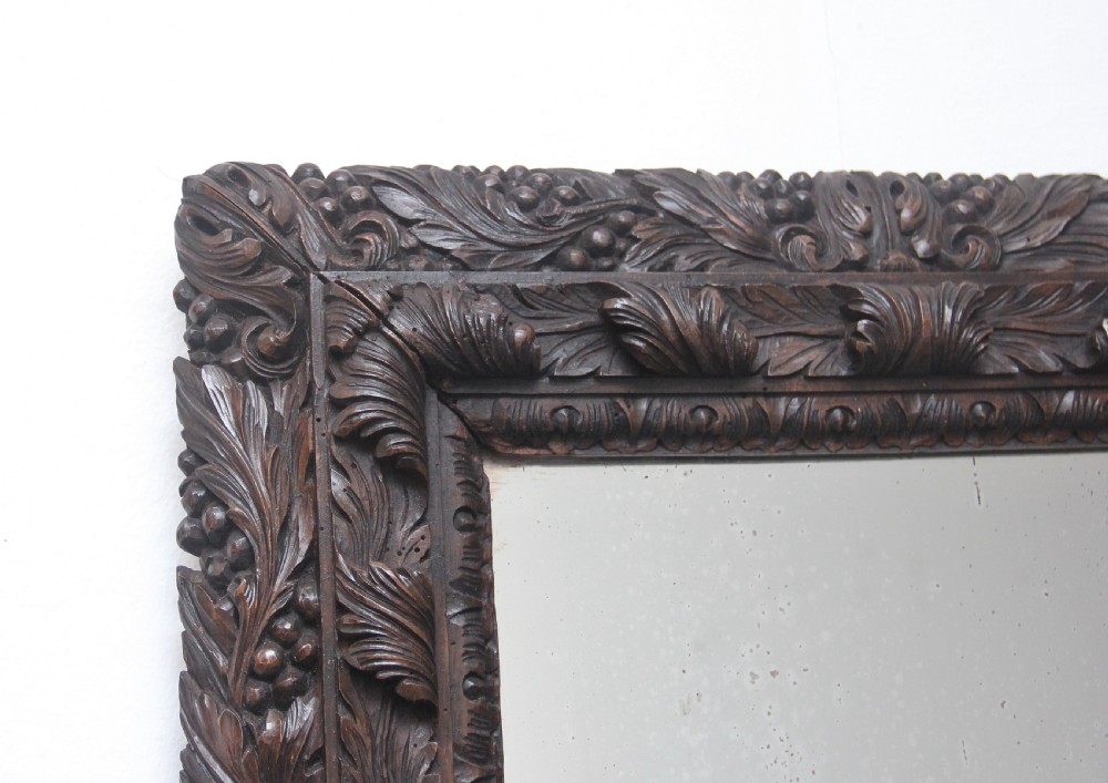 A rectangular 18th century wall mirror featuring a deeply carved dark oak frame with acanthus leaf motifs. View III