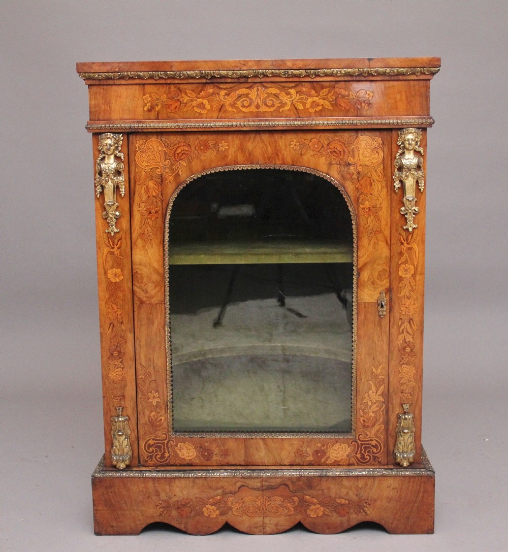 A nineteenth-century walnut pier cabinet featuring intricate floral marquetry, gilt metal mounts, and a central glazed door.