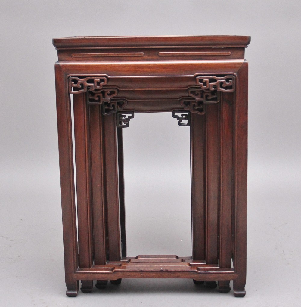 A graduating set of four dark hardwood Chinese nesting tables featuring carved corner spandrels and stepped stretchers. View II