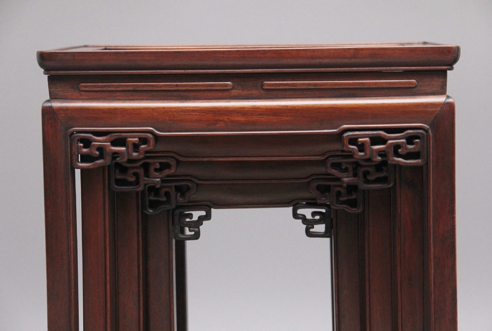 A graduating set of four dark hardwood Chinese nesting tables featuring carved corner spandrels and stepped stretchers. View III