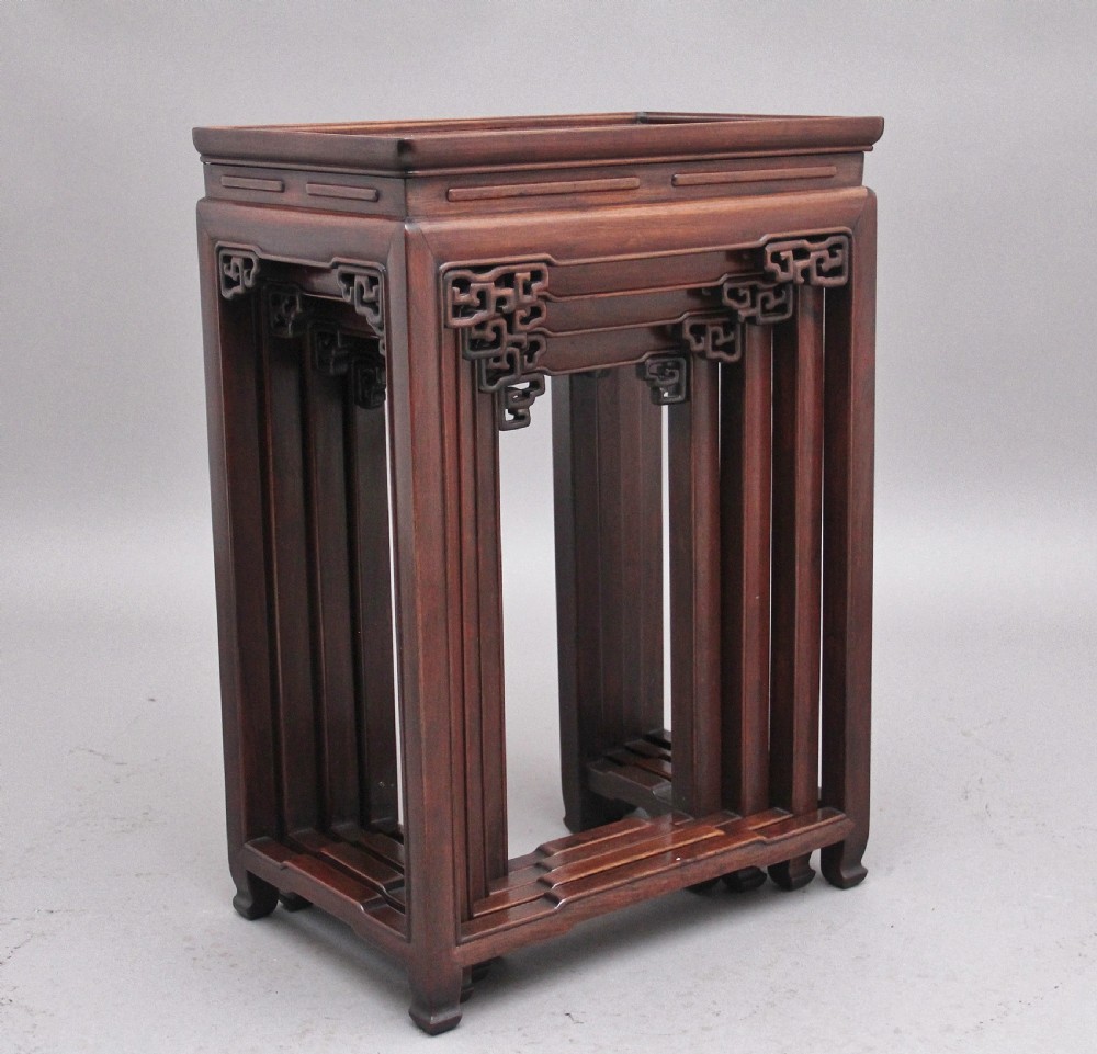 A graduating set of four dark hardwood Chinese nesting tables featuring carved corner spandrels and stepped stretchers. View IV