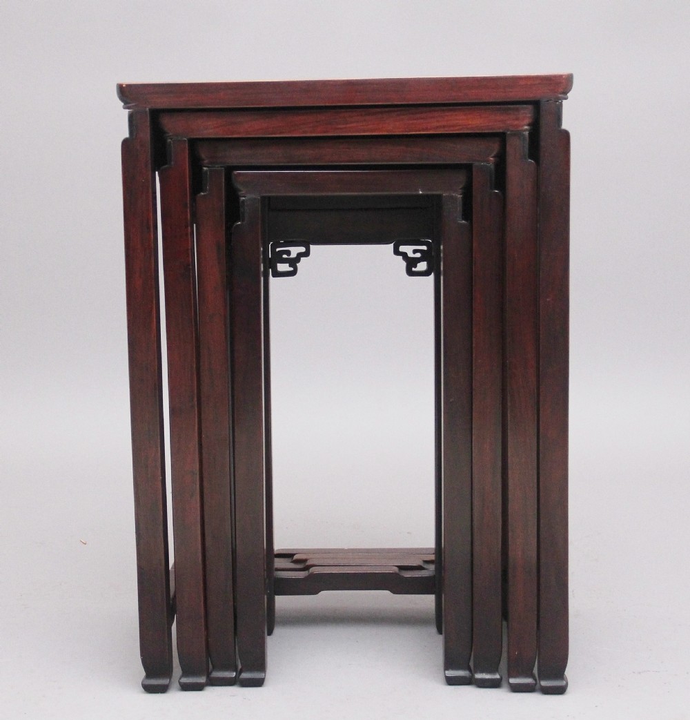 A graduating set of four dark hardwood Chinese nesting tables featuring carved corner spandrels and stepped stretchers. View VI