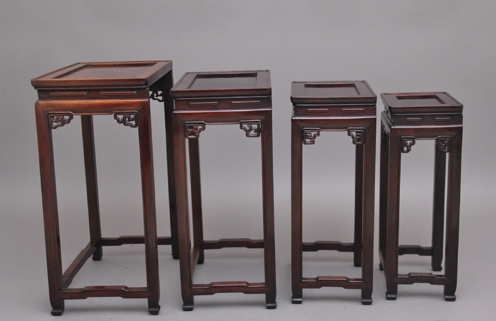 A graduating set of four dark hardwood Chinese nesting tables featuring carved corner spandrels and stepped stretchers. View VIII