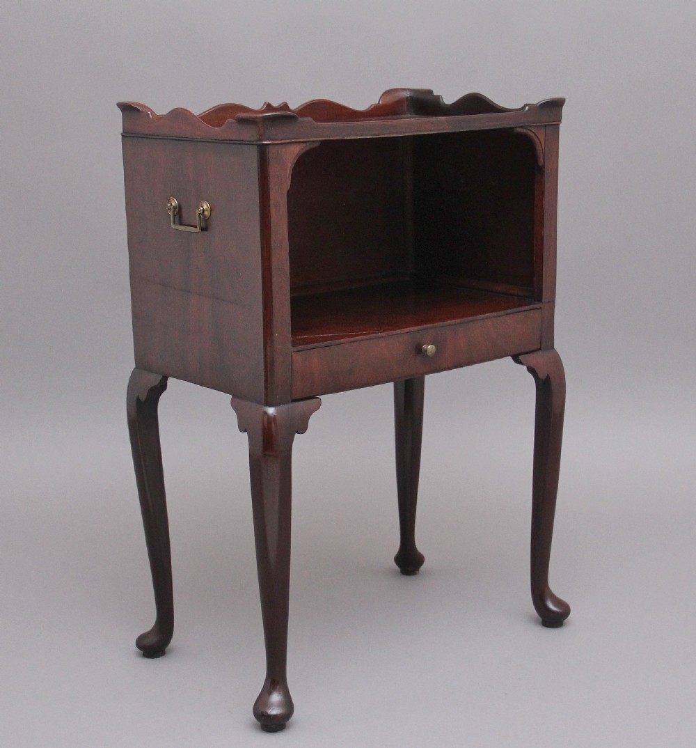 An early 20th-century Georgian-style mahogany bedside cabinet with a scalloped gallery top, open compartment, drawer, brass side handles, and cabriole legs.