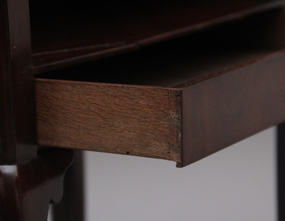 An early 20th-century Georgian-style mahogany bedside cabinet with a scalloped gallery top, open compartment, drawer, brass side handles, and cabriole legs. View IX