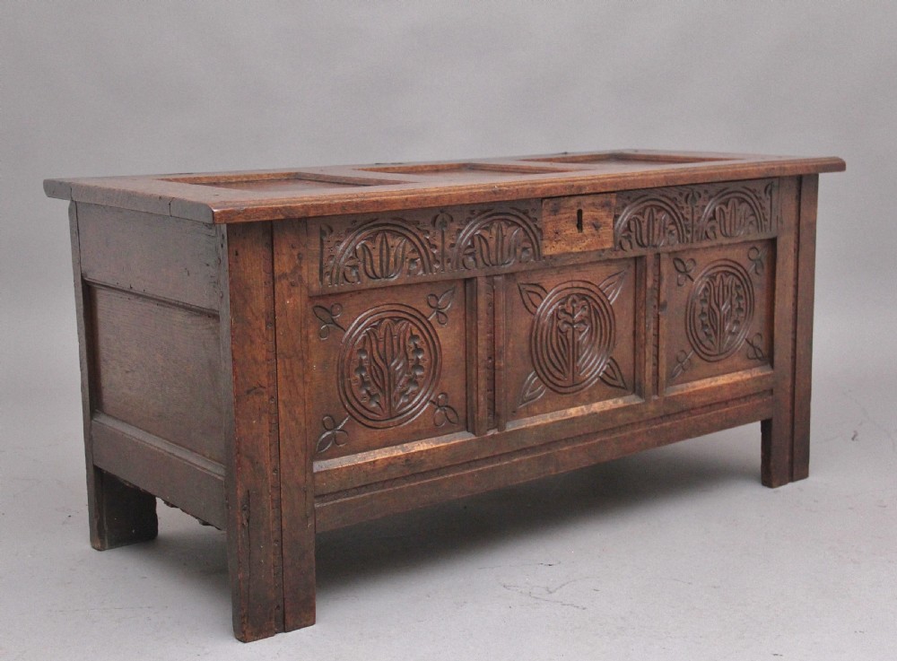 A 17th-century dark oak coffer featuring three carved geometric front panels and a paneled hinged top. View II
