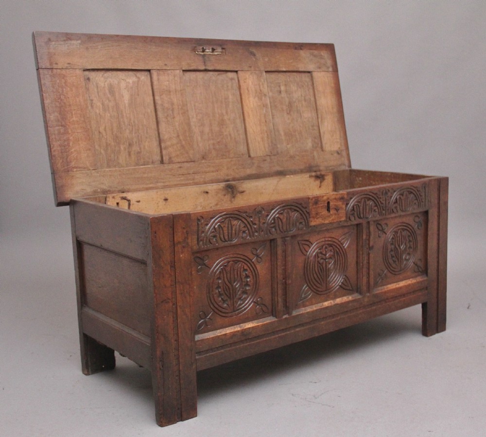 A 17th-century dark oak coffer featuring three carved geometric front panels and a paneled hinged top. View III