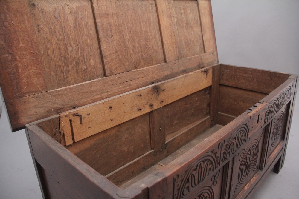 A 17th-century dark oak coffer featuring three carved geometric front panels and a paneled hinged top. View IV
