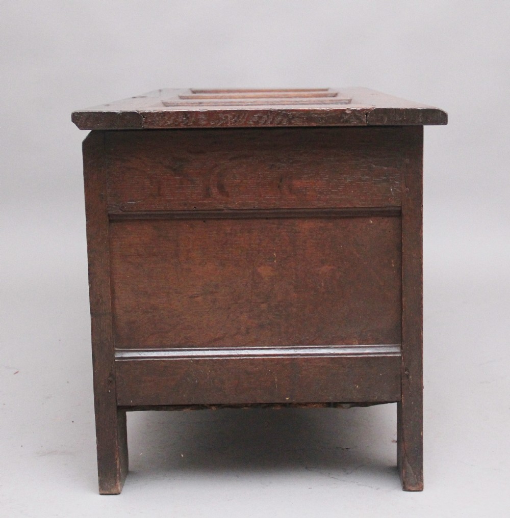 A 17th-century dark oak coffer featuring three carved geometric front panels and a paneled hinged top. View VI