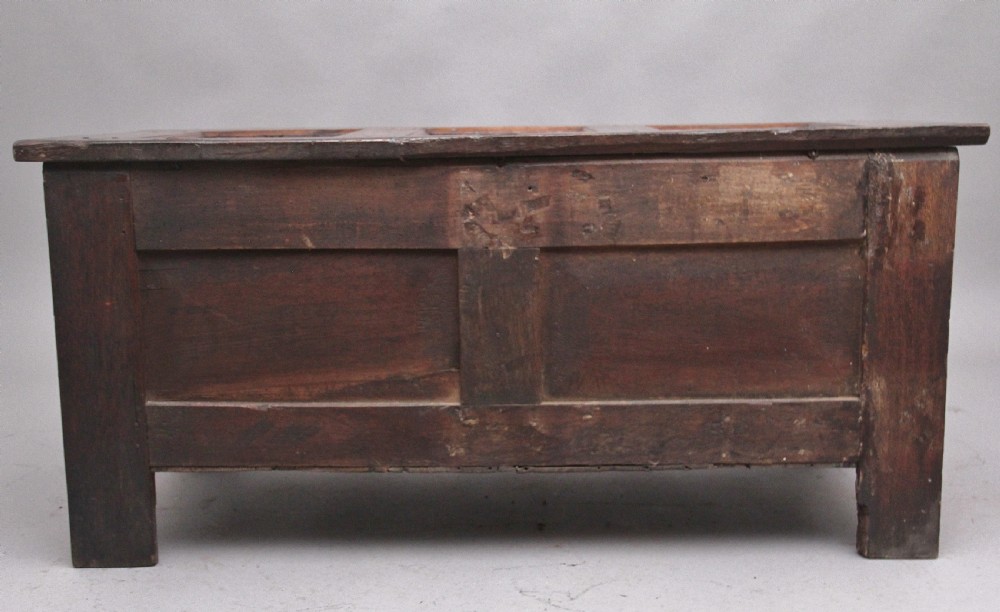 A 17th-century dark oak coffer featuring three carved geometric front panels and a paneled hinged top. View VII