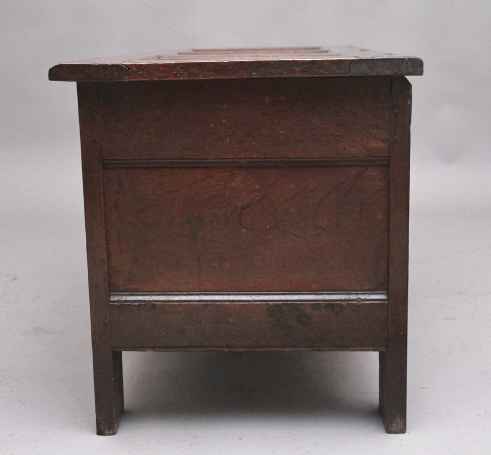 A 17th-century dark oak coffer featuring three carved geometric front panels and a paneled hinged top. View VIII
