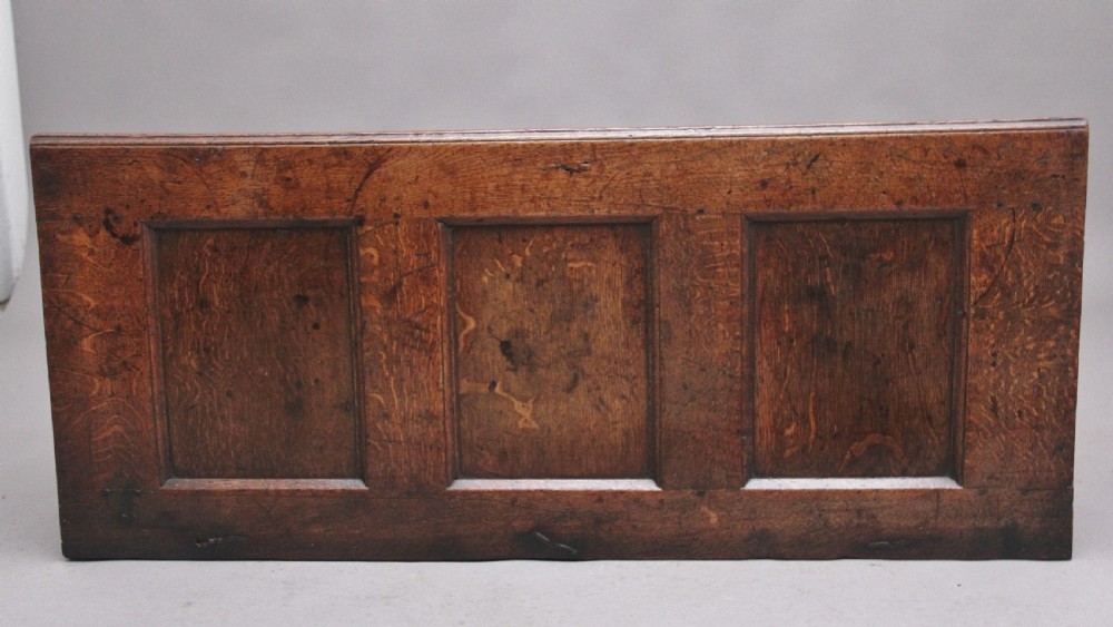 A 17th-century dark oak coffer featuring three carved geometric front panels and a paneled hinged top. View IX