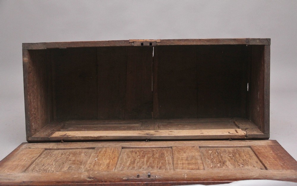 A 17th-century dark oak coffer featuring three carved geometric front panels and a paneled hinged top. View X