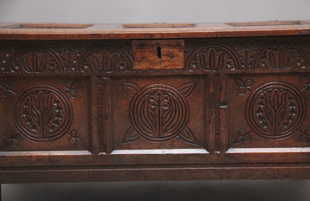 A 17th-century dark oak coffer featuring three carved geometric front panels and a paneled hinged top. View XI