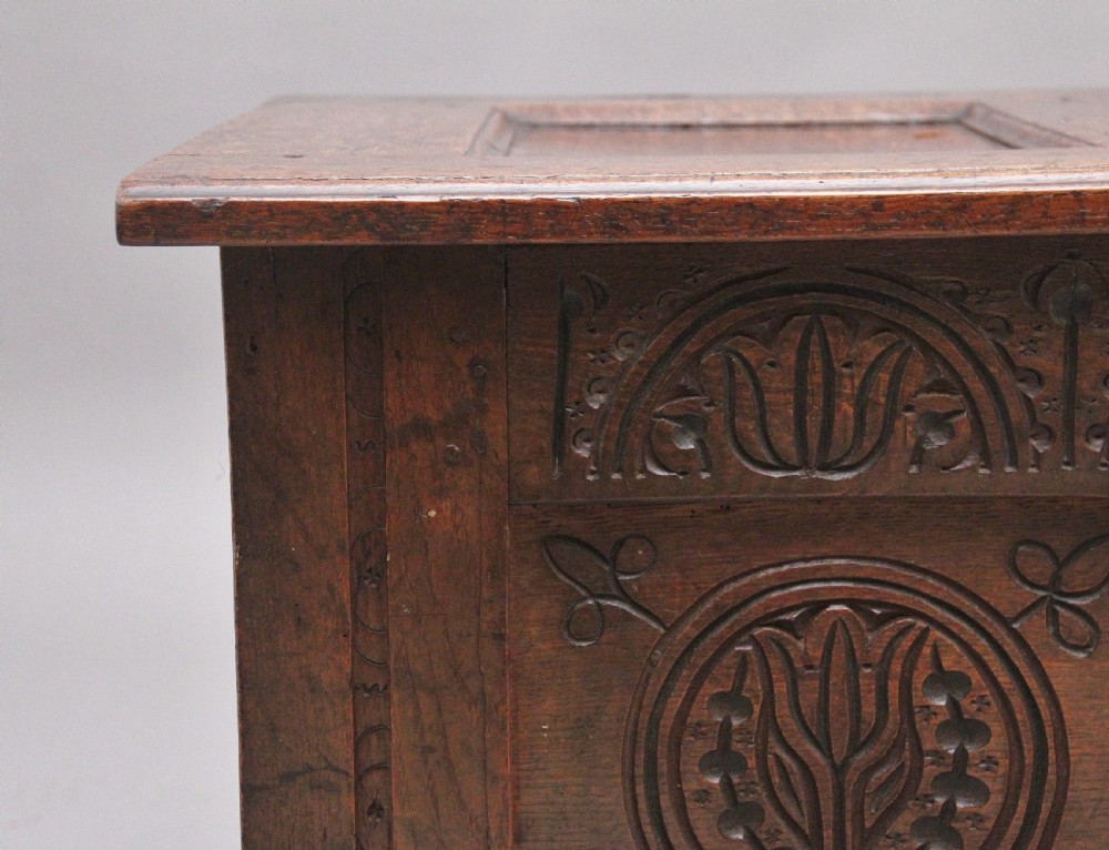 A 17th-century dark oak coffer featuring three carved geometric front panels and a paneled hinged top. View XII