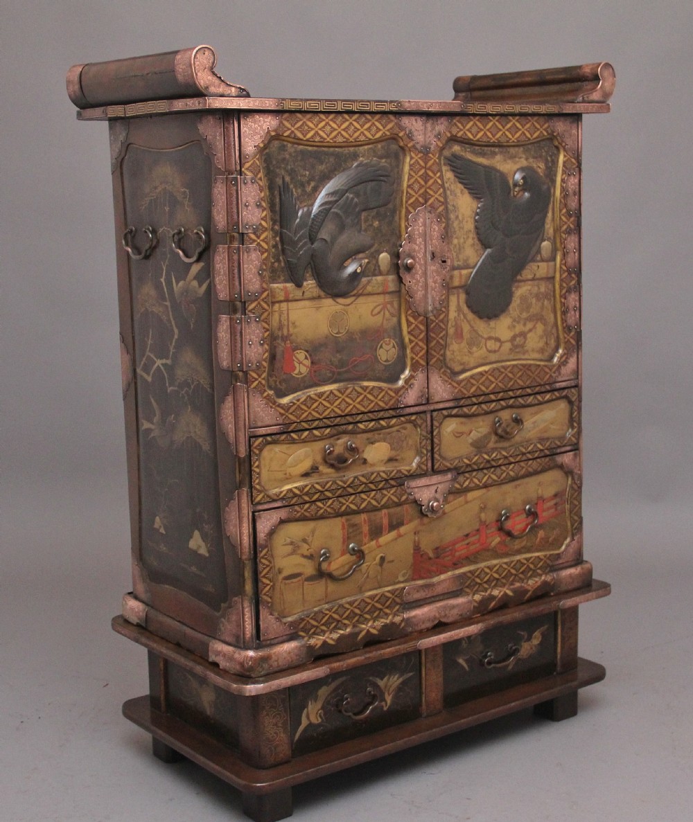 A 19th-century Japanese gilt lacquer tabletop cabinet featuring double doors with high-relief carved birds, several drawers, and decorative copper corner mounts. View II