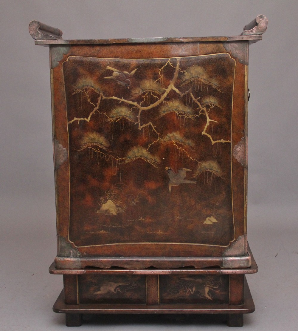 A 19th-century Japanese gilt lacquer tabletop cabinet featuring double doors with high-relief carved birds, several drawers, and decorative copper corner mounts. View VI