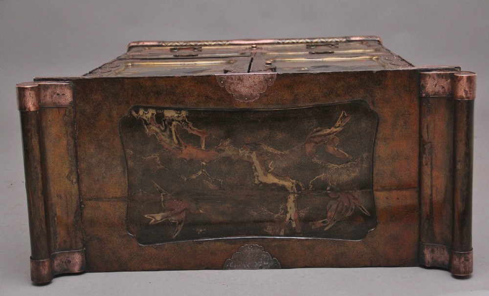 A 19th-century Japanese gilt lacquer tabletop cabinet featuring double doors with high-relief carved birds, several drawers, and decorative copper corner mounts. View IX