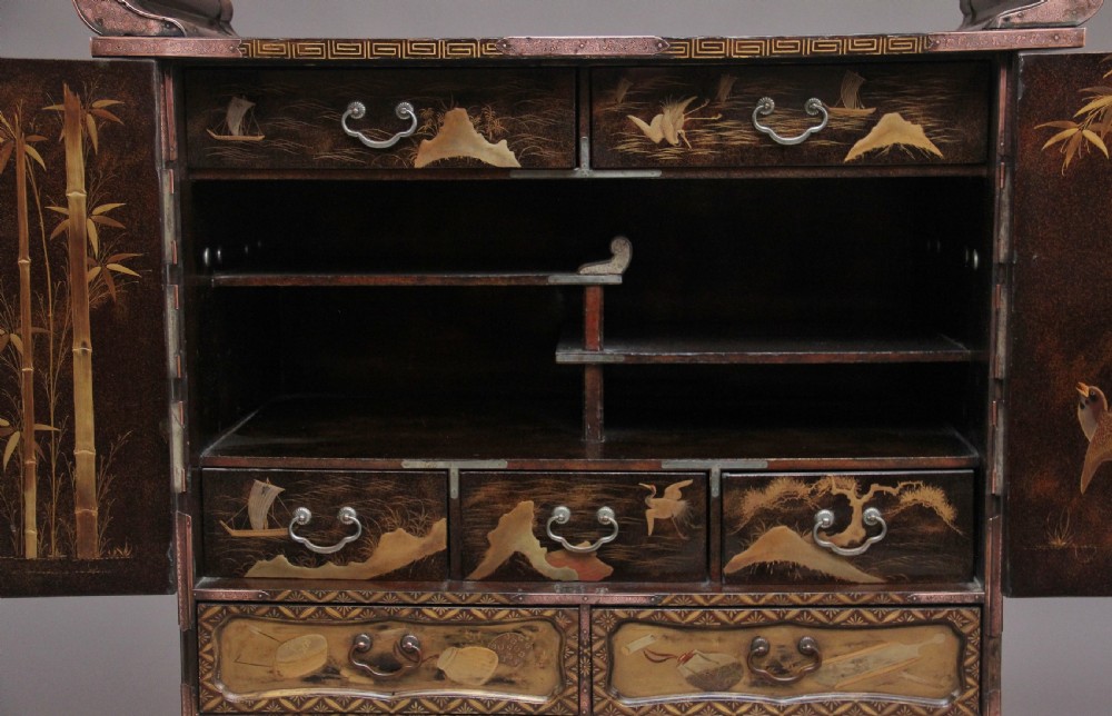 A 19th-century Japanese gilt lacquer tabletop cabinet featuring double doors with high-relief carved birds, several drawers, and decorative copper corner mounts. View X