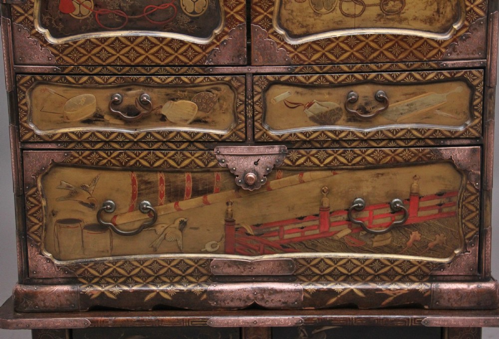 A 19th-century Japanese gilt lacquer tabletop cabinet featuring double doors with high-relief carved birds, several drawers, and decorative copper corner mounts. View XII