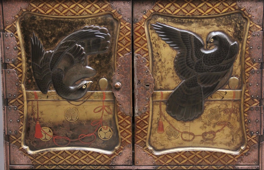 A 19th-century Japanese gilt lacquer tabletop cabinet featuring double doors with high-relief carved birds, several drawers, and decorative copper corner mounts. View XIV