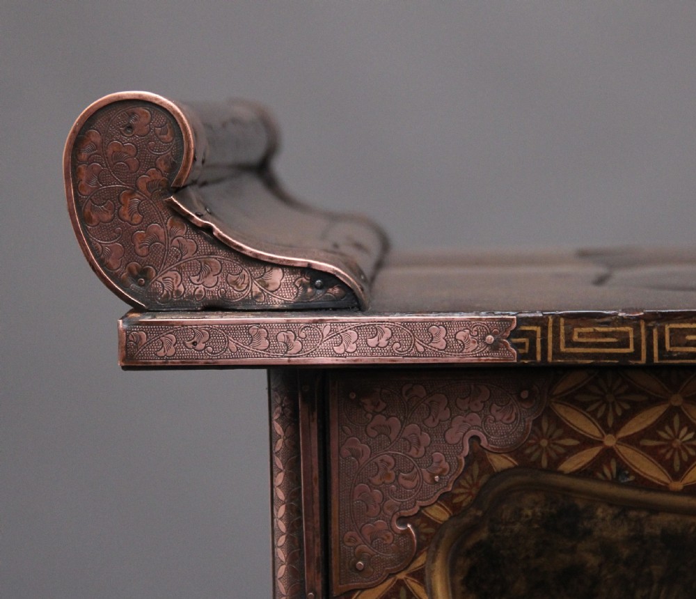 A 19th-century Japanese gilt lacquer tabletop cabinet featuring double doors with high-relief carved birds, several drawers, and decorative copper corner mounts. View XVII